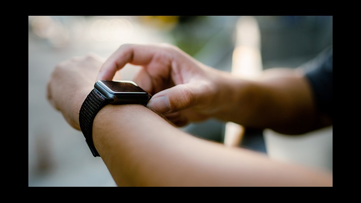 man kijkt naar smartwatch om zijn pols